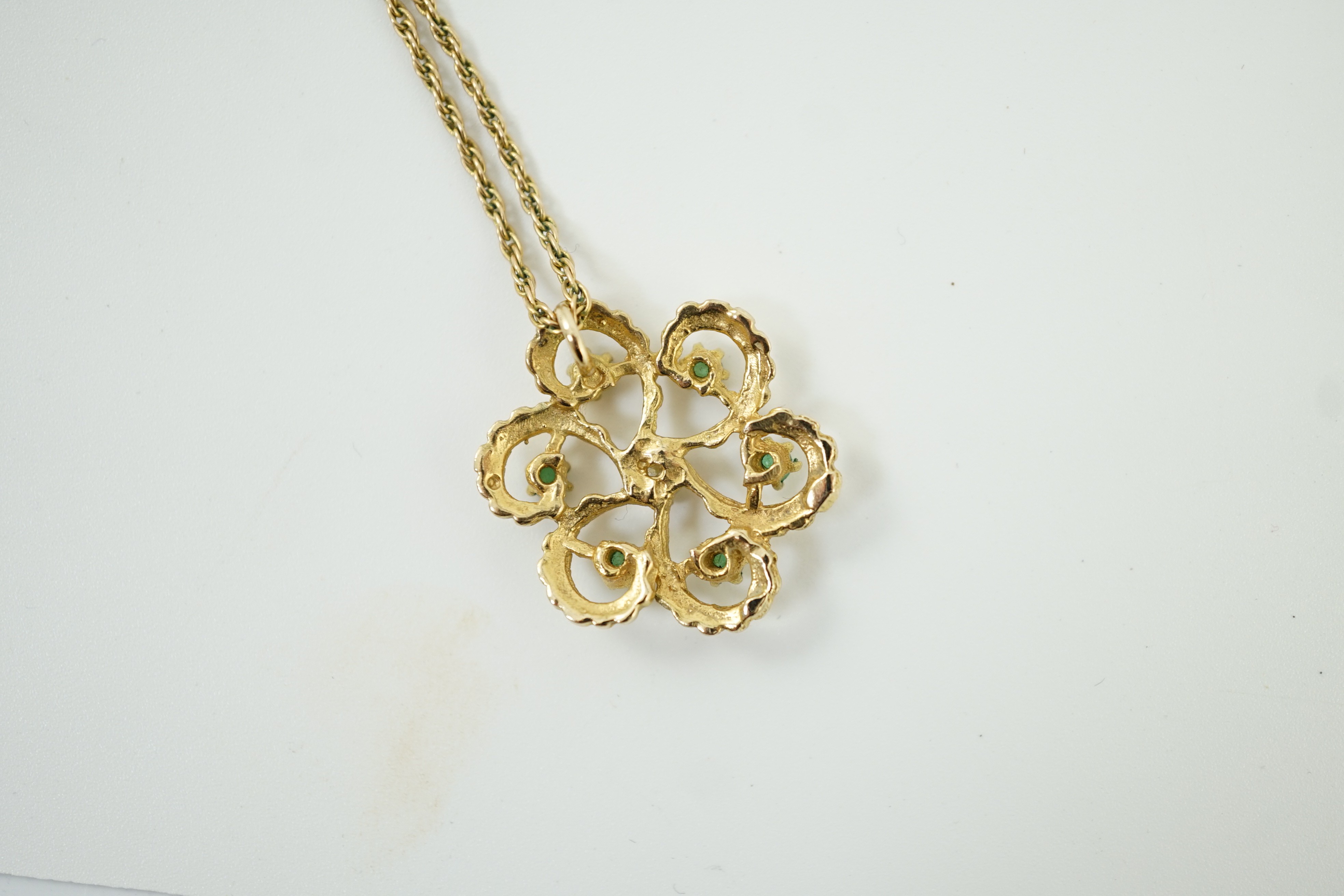 A modern yellow metal, emerald and diamond set stylised flower head pendant, 25mm, on a 375 chain, 46cm, gross weight 6.7 grams.